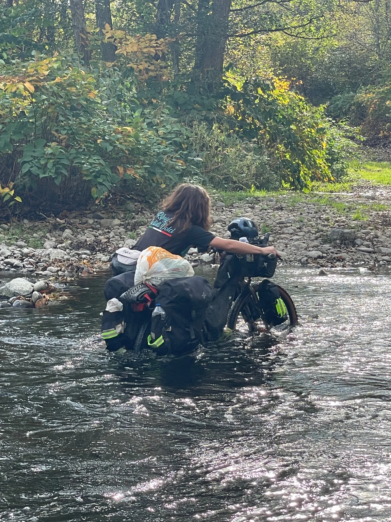 Bike traveller pushing a loaded bicycle through a river crossing