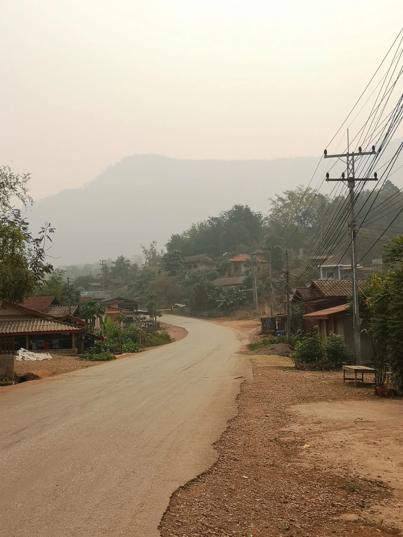 Dusty road through a village with hills in the background